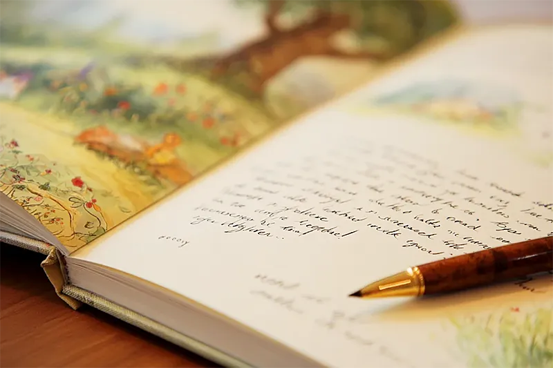 A close-up of the inside cover of an open picture book, showing handwritten text in neat cursive — an inscription. The handwriting is clear and warm, suggesting care and thought. A pen rests nearby. The surrounding book cover is beautifully illustrated, clearly a quality personalized children's book. Warm natural light. The quality of something personal and permanent — words that will be read many times in different decades.